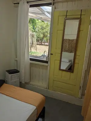 a bedroom with a yellow door and a mirror at Hostel Los Pargos in Río Sequito