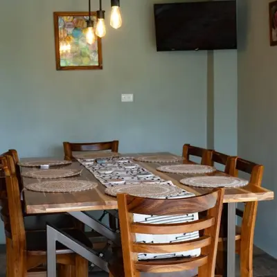 a dining room table with chairs and a television at Casa Amanecer Familiar Hotel Ecopaisajes in Río Cuarto