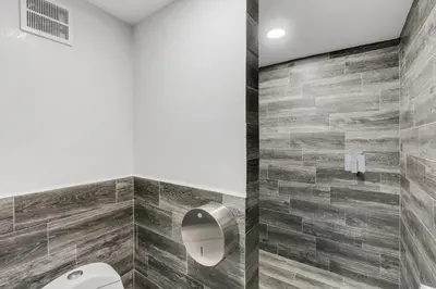 a bathroom with a toilet and a tile wall at Iguana Surf Camp in Tamarindo