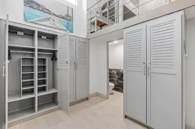 a walk in closet with white cabinets and a toilet at Iguana Surf Camp in Tamarindo