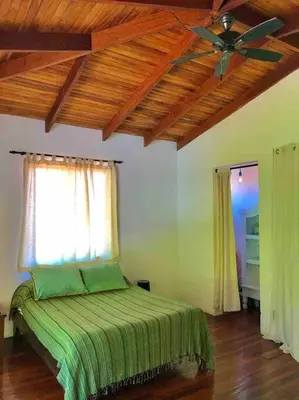 a bedroom with a green bed with a ceiling fan at Lofty, fully equipped apartment in the heart of Montezuma in Puntarenas