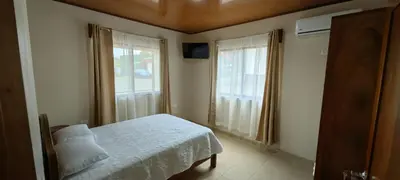 a bedroom with a bed and two large windows at Casita el Corral in Nuevo Arenal