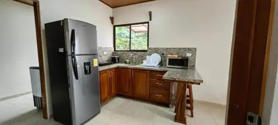 a kitchen with a stainless steel refrigerator and wooden cabinets at Casita el Corral in Nuevo Arenal