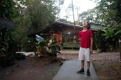 a boy standing on a sidewalk in front of a house at Santuario Ecologico Monteverde in Monteverde Costa Rica