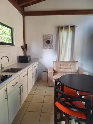 a kitchen with a sink and a table and a couch at La cabaña del Dulce in San Rafael Norte