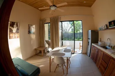 a kitchen and living room with a table and a refrigerator at La Laguna in Nosara