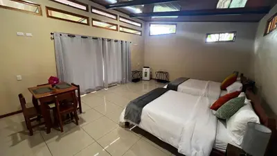 a bedroom with a bed and a table and windows at Chirripó Oasis in Canaán