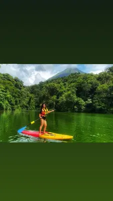 a woman on a paddle board in the water at Paraíso privado Arenal Dragonfly in Fortuna