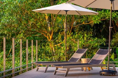 two chairs and an umbrella on a patio at Villa Vista Del Mar - by Pura Villas in Dominical