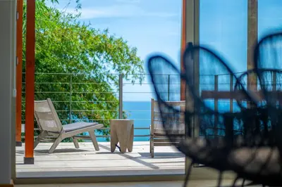 a patio with a chair and a table and a view of the ocean at Villa Vista Del Mar - by Pura Villas in Dominical