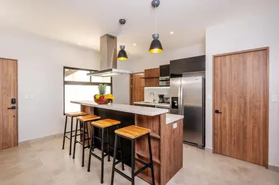 a kitchen with a counter with stools and a refrigerator at Villa Maravilla Estates, Tamarindo Beach, Prime Location, Family & Friends in Tamarindo