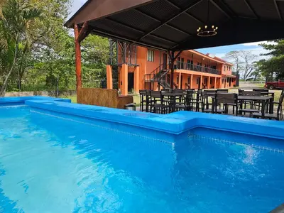 a swimming pool with tables and chairs and a building at Hotel Luna Liberiana in Liberia