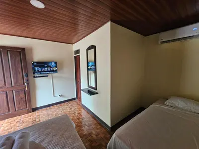 a bedroom with two beds and a tv on the wall at Hotel Luna Liberiana in Liberia