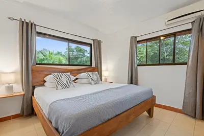 a bedroom with a bed and two windows at Villas Vibras in Playa Avellana