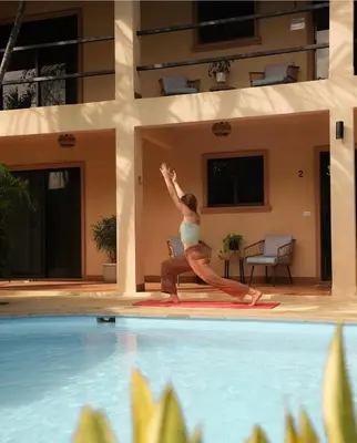 a woman standing on a yoga pose next to a swimming pool at Villas Vibras in Playa Avellana