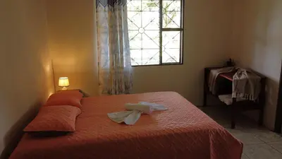 a bedroom with a bed with orange sheets and a window at CañoNegro CasaBlanca in Caño Negro