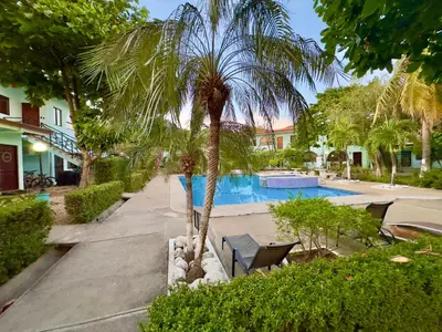 a palm tree sitting next to a swimming pool at Coastal Comfort Spacious Second-Floor Getaway in Coco