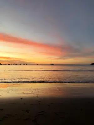 a sunset on the beach with a boat in the water at Coastal Comfort Spacious Second-Floor Getaway in Coco
