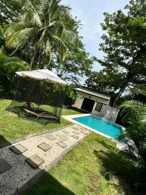 a swimming pool with an umbrella next to a house at Villa Ho Omaika I Los Delfines Tambor in Pochote