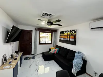 a living room with a black couch and a ceiling fan at Villa Ho Omaika I Los Delfines Tambor in Pochote