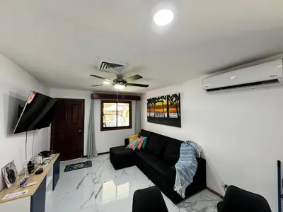 a living room with a black couch and a ceiling fan at Villa Ho Omaika I Los Delfines Tambor in Pochote