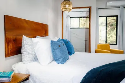 a bedroom with a white bed with blue pillows at Villas Santa Maria - Private Bay Lake Arenal in Nuevo Arenal