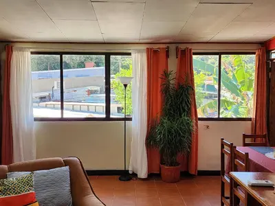 a living room with two windows and a potted plant at Apartamento Casa Laura in Quepos
