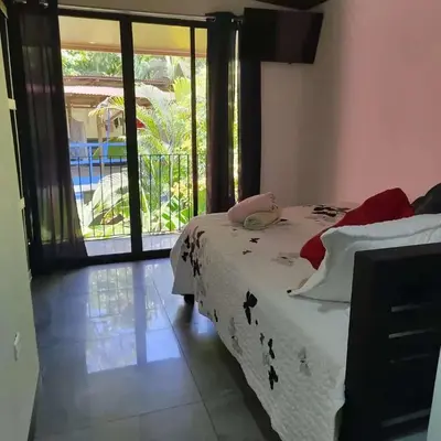a bedroom with a bed and a view of a pool at Cabinas la Antorcha in Dominical