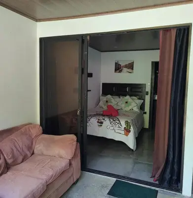 a bedroom with a bed and a couch and a mirror at Cabinas la Antorcha in Dominical