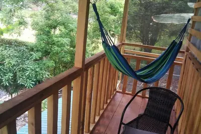 a hammock on a porch with a chair at Rustic wooden little house close to the beach in Uvita