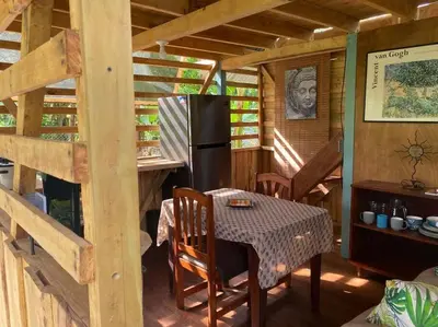 a kitchen with a table and a refrigerator in a cabin at Rustic wooden little house close to the beach in Uvita