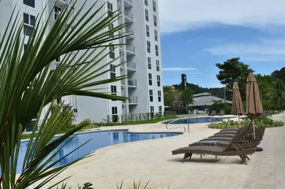 a hotel with chairs and umbrellas next to a pool at Lulo Jaco New ocean view apartment in Jacó