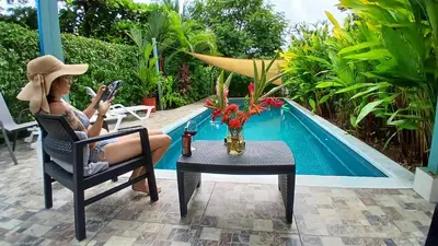 a woman sitting in a chair next to a swimming pool at Apartment with large terrace and garden view in Uvita
