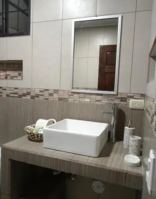 a bathroom with a white sink and a mirror at La Fortuna Raft House in Fortuna