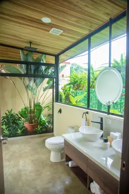 a bathroom with a toilet and two sinks and a mirror at Scenic Volcano Villas with Hot Tub in Fortuna