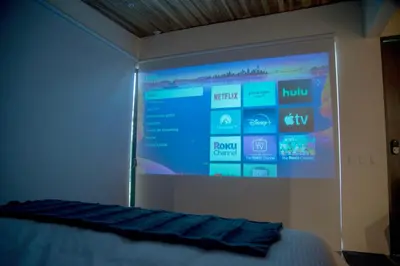 a projection screen in a bedroom with a bed at Scenic Volcano Villas with Hot Tub in Fortuna