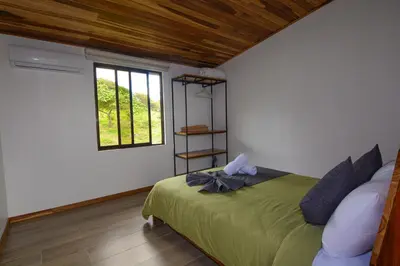 a bedroom with a green bed with a window at Nambí Monteverde in Monteverde Costa Rica