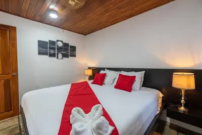 a bedroom with a bed with a red and white blanket at Villa Tucán - La Fortuna in Fortuna