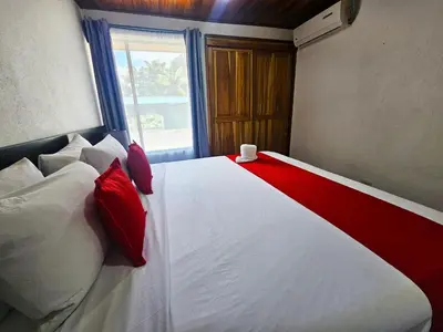 a bedroom with a bed with red and white pillows at Villa Tucán - La Fortuna in Fortuna