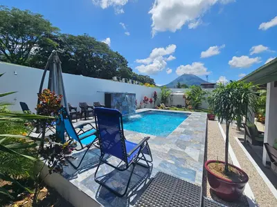 a patio with two chairs and a swimming pool at Villa Tucán - La Fortuna in Fortuna