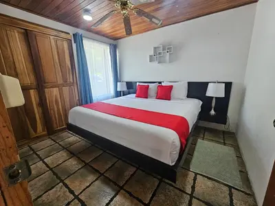a bedroom with a large bed with red pillows at Villa Tucán - La Fortuna in Fortuna