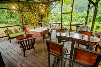 a porch with chairs and a table and a tub at Cabaña Los Tucanes in Fortuna