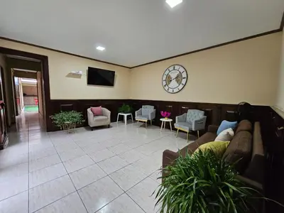 a living room with a couch and a clock on the wall at Hostel La Cali Inn in San José