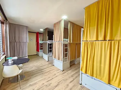 a room with yellow curtains and a table and chairs at Hostel La Cali Inn in San José
