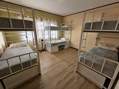 a room with three bunk beds and a wooden floor at Hostel La Cali Inn in San José