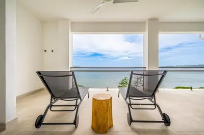 two chairs and a table in a room with a view of the ocean at Golden Palms#10 in Playa Flamingo