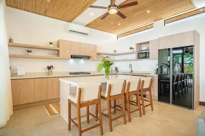 an open kitchen with a large island with bar stools at Villa Juntos in Tamarindo