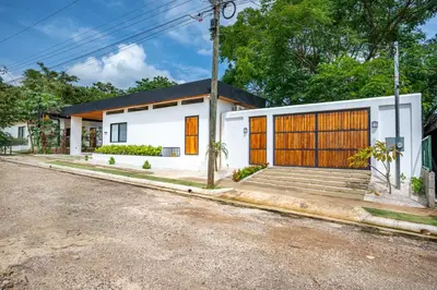 a white house with orange doors and a driveway at Villa Juntos in Tamarindo
