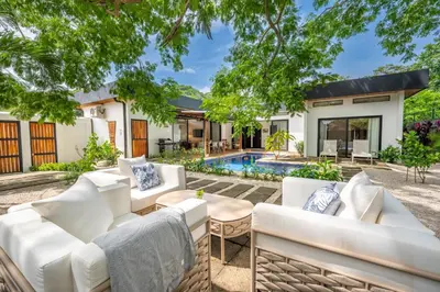 an outdoor patio with white furniture and a swimming pool at Villa Juntos in Tamarindo