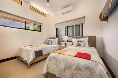 a bedroom with two beds and a window at Villa Juntos in Tamarindo